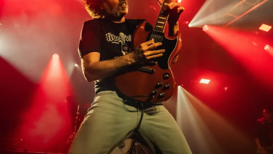 Guitarrista en pleno directo bajo luz roja en un concierto de Get Rock