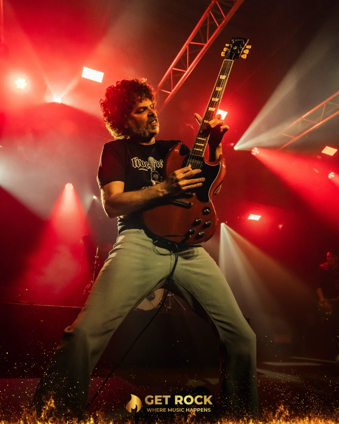 Guitarrista en pleno directo bajo luz roja en un concierto de Get Rock